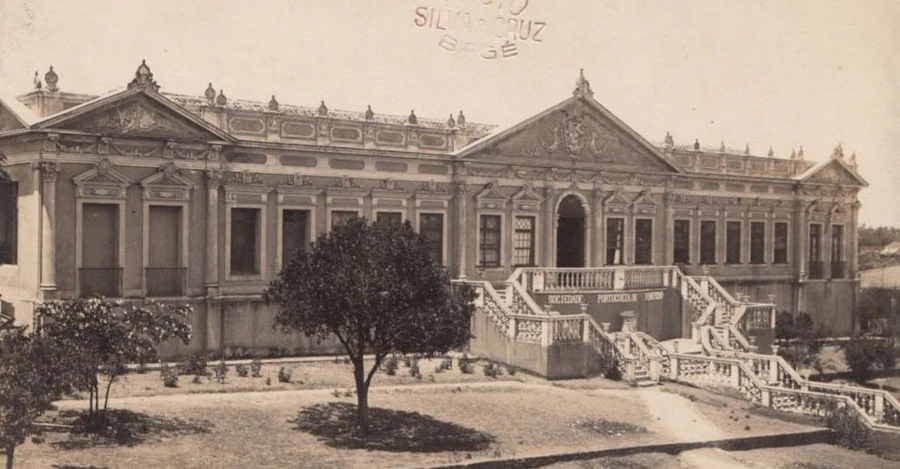 Foto antiga da Sociedade Portuguesa de Bagé mostrando a fachada original e a escadaria do prédio histórico no início do século XX.
